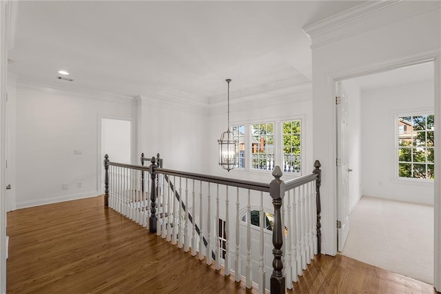 staircase featuring an inviting chandelier, hardwood / wood-style floors, a wealth of natural light, and crown molding