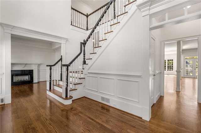 staircase with a high ceiling, hardwood / wood-style floors, and crown molding