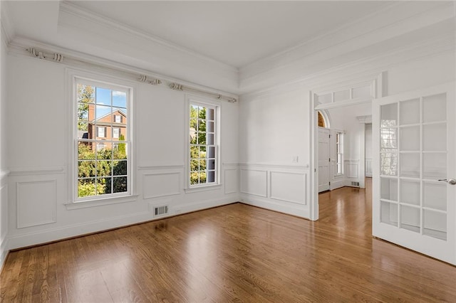 empty room featuring hardwood / wood-style floors, a healthy amount of sunlight, and ornamental molding