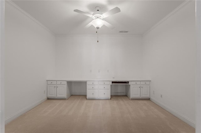 unfurnished office featuring built in desk, light carpet, ceiling fan, and crown molding