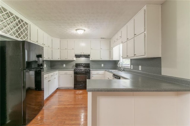 10 Briarcliff Pl, Stockbridge, GA 30281 - kitchen featuring black appliances, under cabinet range hood, a textured ceiling, a peninsula, and light wood finished floors