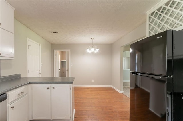 10 Briarcliff Pl, Stockbridge, GA 30281 - kitchen with freestanding refrigerator, white cabinets, a peninsula, light wood-type flooring, and a textured ceiling