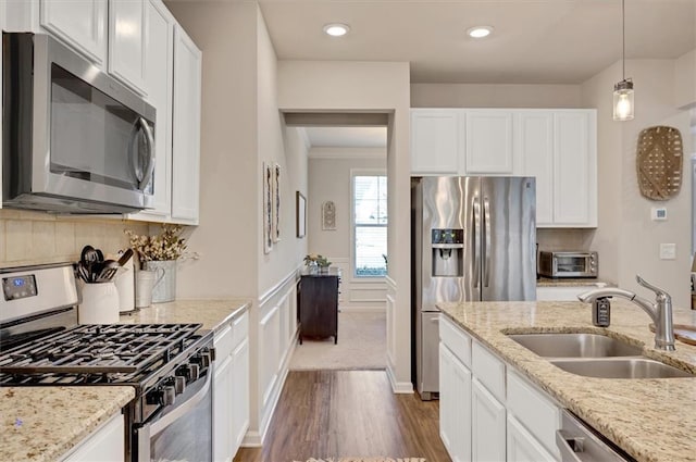 kitchen featuring sink, stainless steel appliances, white cabinets, and light stone countertops