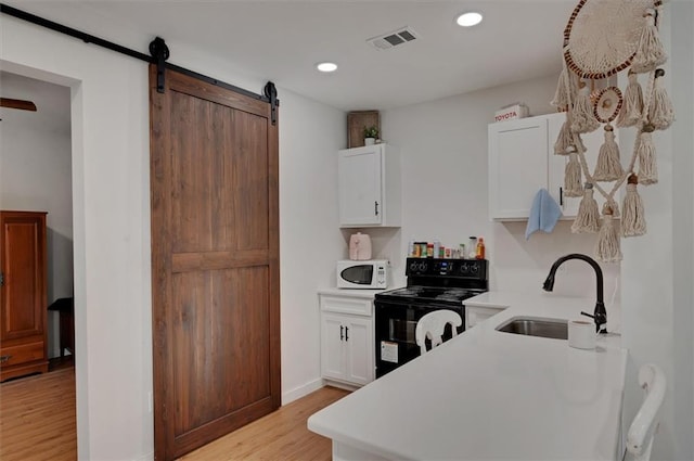 kitchen with white cabinets, electric range, a barn door, and sink