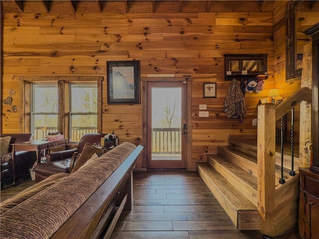 interior space with dark wood-style floors, stairway, and wooden walls