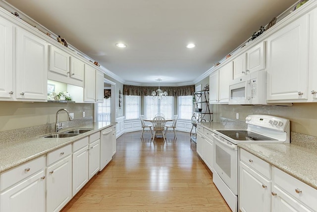 kitchen with light wood-type flooring, white appliances, decorative light fixtures, and white cabinets