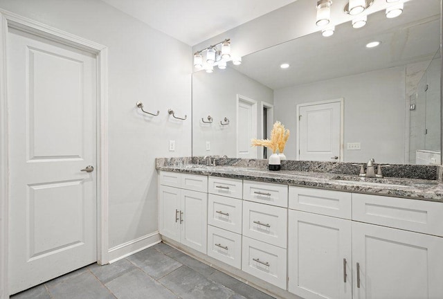 bathroom featuring double vanity, a stall shower, and baseboards