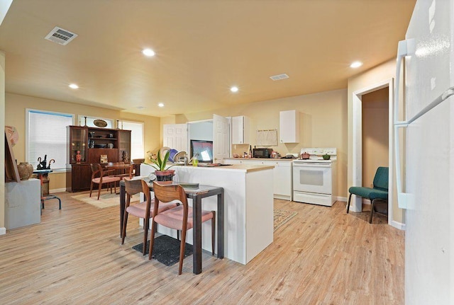 kitchen featuring white appliances, white cabinets, light wood finished floors, light countertops, and recessed lighting