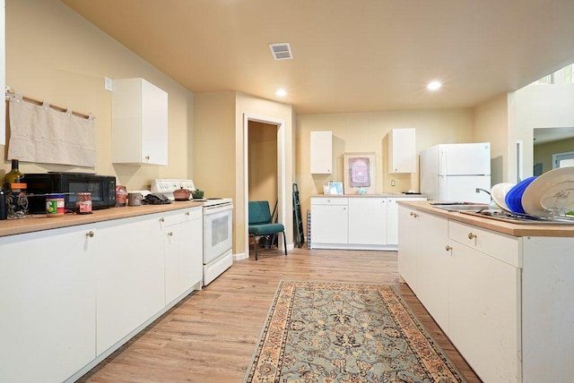 kitchen featuring white appliances, light wood finished floors, a sink, white cabinets, and recessed lighting