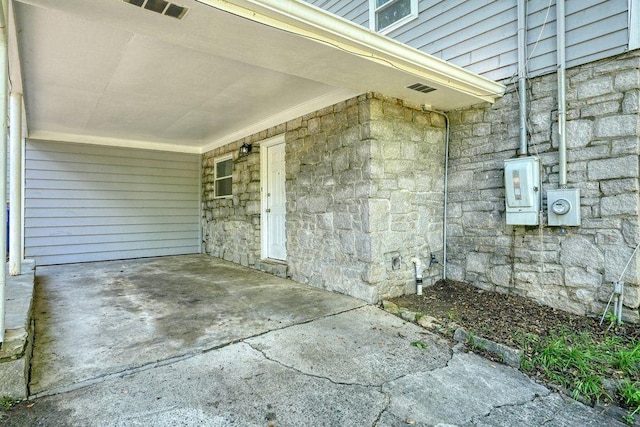 entrance to property with stone siding and a carport