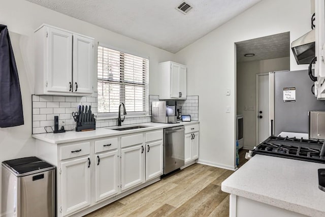 kitchen featuring visible vents, light wood-style flooring, a sink, white cabinetry, and stainless steel appliances