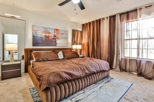 bedroom featuring light carpet, a textured ceiling, and a ceiling fan