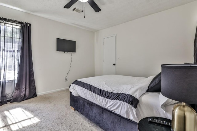 carpeted bedroom with visible vents, baseboards, a textured ceiling, and ceiling fan