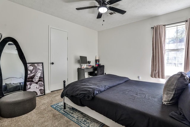 carpeted bedroom featuring visible vents, a textured ceiling, and a ceiling fan