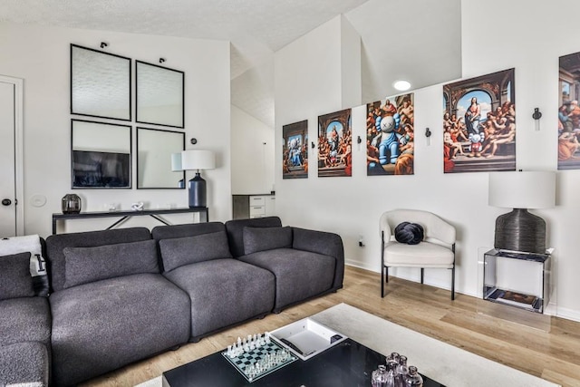 living area featuring vaulted ceiling, baseboards, and wood finished floors