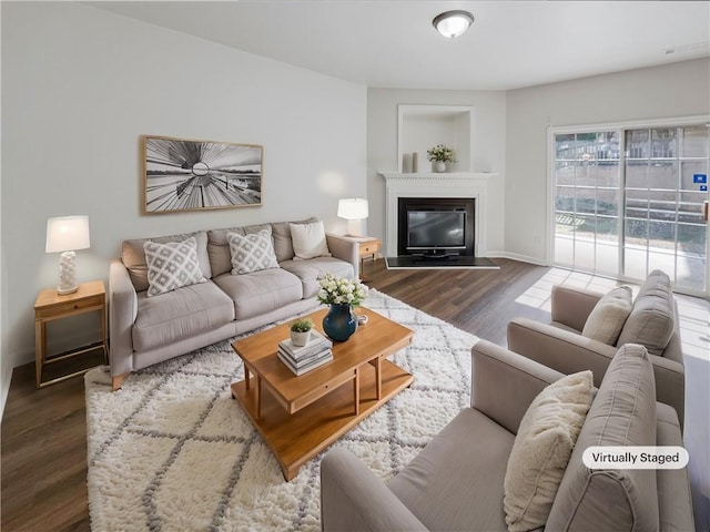 living room featuring a glass covered fireplace, wood finished floors, and baseboards