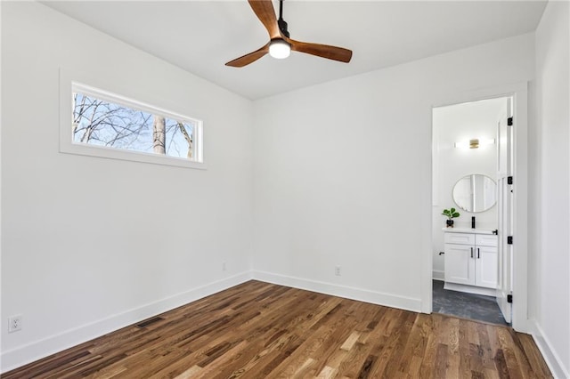 unfurnished bedroom with dark wood-style floors, ceiling fan, ensuite bathroom, and baseboards