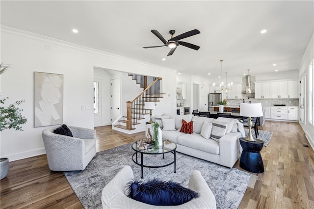 living room featuring recessed lighting, stairway, wood finished floors, and ornamental molding