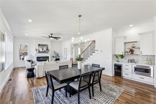 dining space with wine cooler, a glass covered fireplace, and crown molding