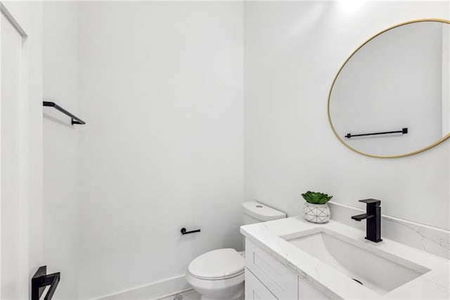 half bathroom with toilet, marble finish floor, baseboards, and vanity