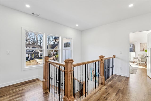 corridor with recessed lighting, visible vents, an upstairs landing, and wood finished floors