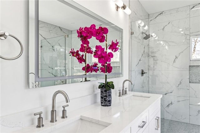 full bath with double vanity, a marble finish shower, and a sink