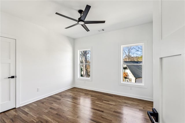 unfurnished bedroom with dark wood-style floors, visible vents, and multiple windows