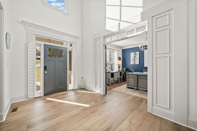 foyer featuring light hardwood / wood-style floors, a wealth of natural light, and ornamental molding