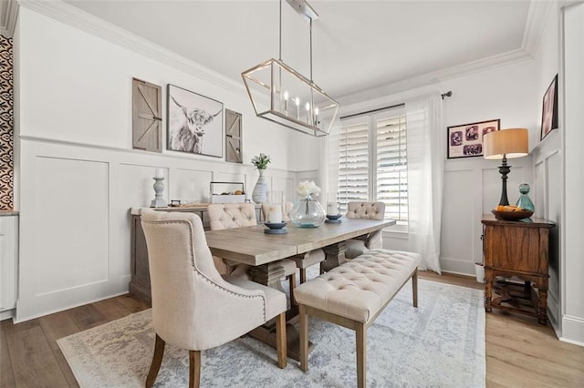 dining space with hardwood / wood-style floors, a notable chandelier, and ornamental molding