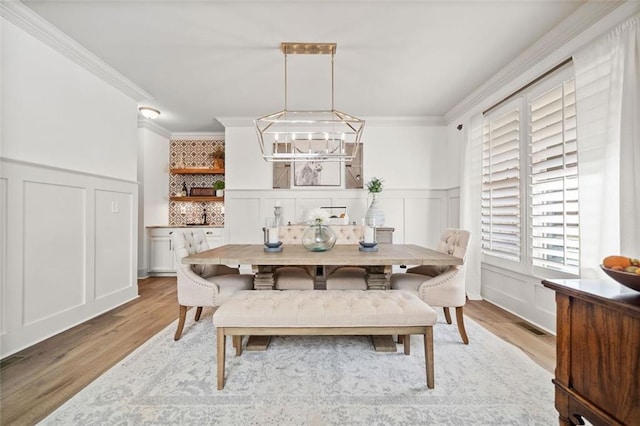 dining room with a chandelier, light hardwood / wood-style floors, and ornamental molding