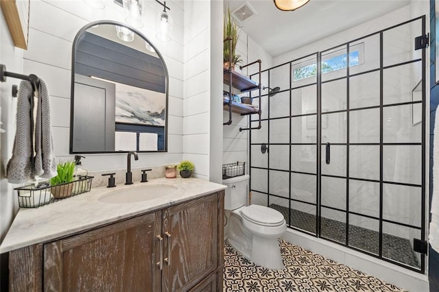 bathroom featuring vanity, toilet, tiled shower, and tile walls