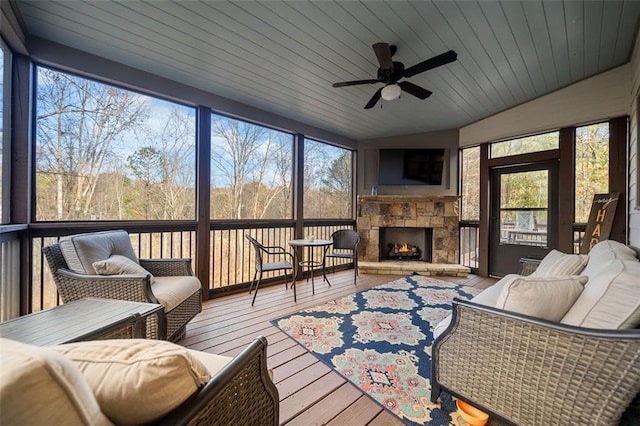 sunroom with a fireplace, plenty of natural light, lofted ceiling, and ceiling fan