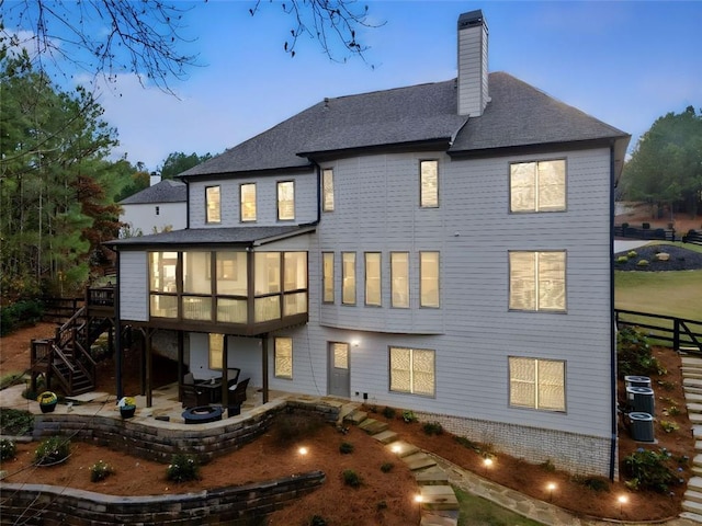 back house at dusk featuring a patio and central AC