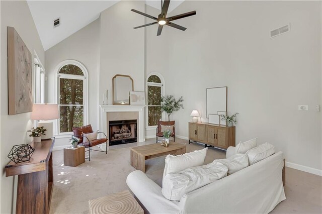 living room featuring a towering ceiling, plenty of natural light, and light colored carpet