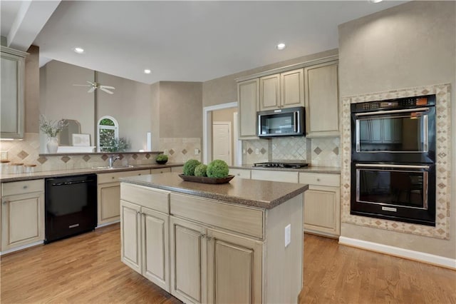 kitchen featuring light hardwood / wood-style floors, black appliances, cream cabinetry, and a center island