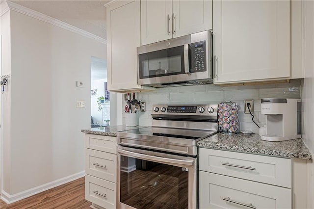 kitchen featuring stainless steel appliances, crown molding, tasteful backsplash, baseboards, and light stone countertops