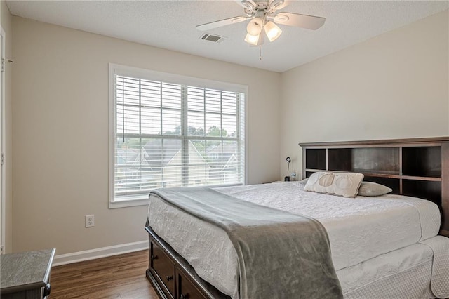 bedroom featuring multiple windows, dark wood-style flooring, baseboards, and a ceiling fan