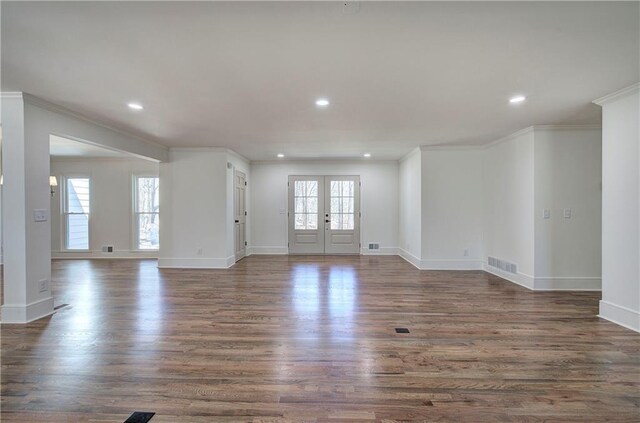 unfurnished living room with visible vents, ornamental molding, wood finished floors, and french doors