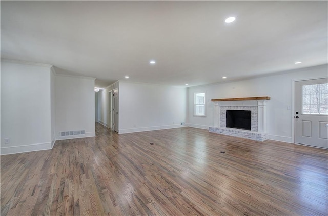 unfurnished living room featuring a brick fireplace, visible vents, and wood finished floors