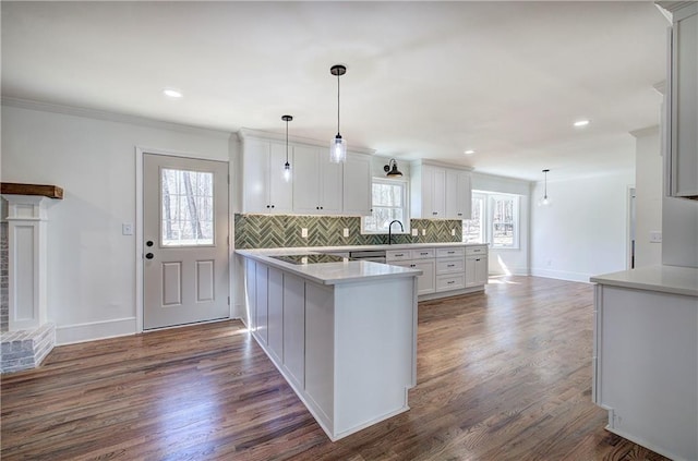 kitchen with dark wood-style floors, a peninsula, light countertops, and decorative backsplash