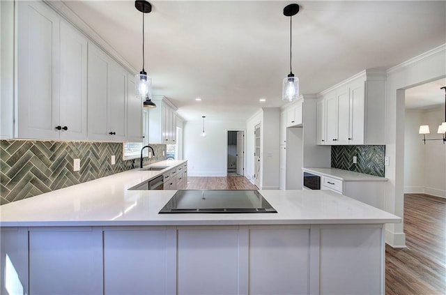 kitchen with a peninsula, wood finished floors, white cabinets, light countertops, and stovetop