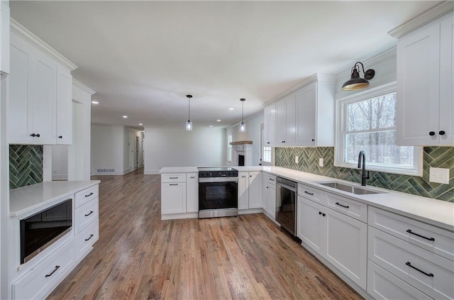 kitchen with range with electric stovetop, light wood-style flooring, a sink, dishwasher, and a peninsula