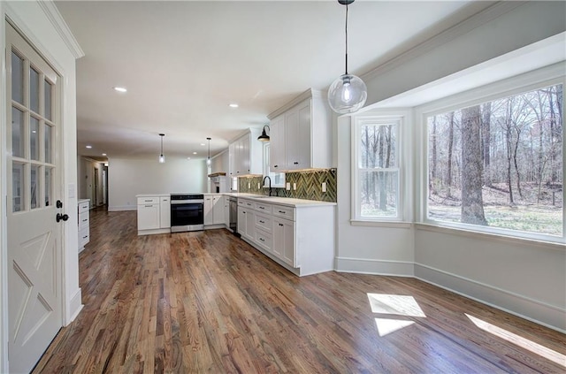 kitchen with tasteful backsplash, oven, a peninsula, light countertops, and stainless steel dishwasher