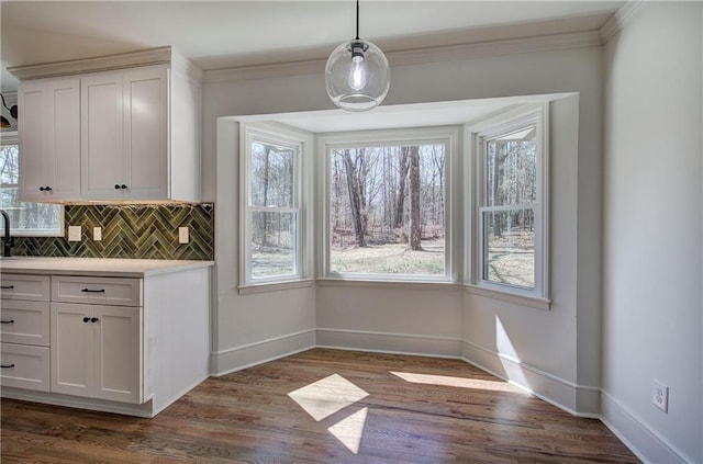 unfurnished dining area with dark wood-style floors, baseboards, and ornamental molding