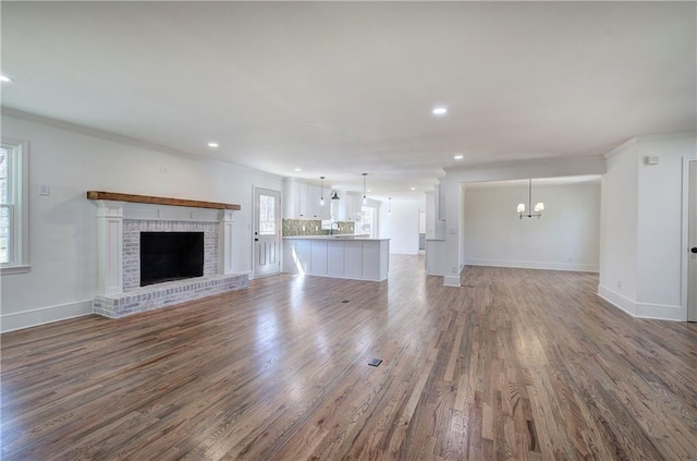 unfurnished living room featuring baseboards, wood finished floors, crown molding, a fireplace, and recessed lighting