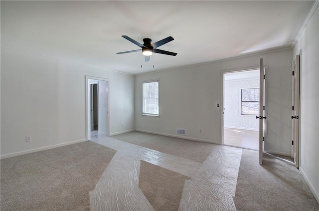 empty room featuring ornamental molding, light colored carpet, visible vents, and baseboards