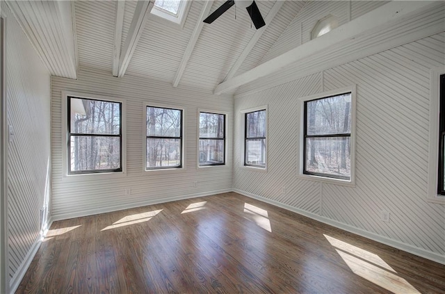 unfurnished room featuring a ceiling fan, vaulted ceiling with skylight, dark wood finished floors, and baseboards