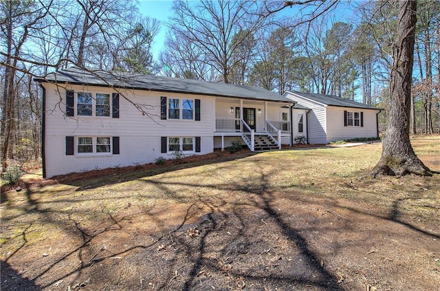 view of front facade with a front yard, covered porch, and brick siding