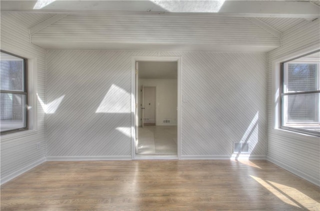 spare room with baseboards and wood finished floors