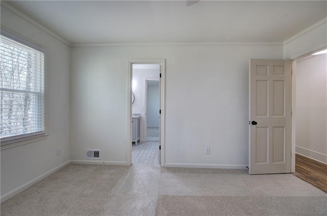 unfurnished bedroom with carpet, multiple windows, crown molding, and visible vents